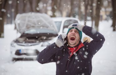 Man looking stressed because his car is broken down in winter
