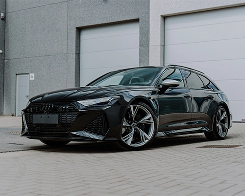 Black Audi RS6 parked in front of garage bay doors