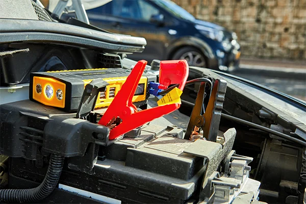 Car battery with jumper cables attached to each terminal