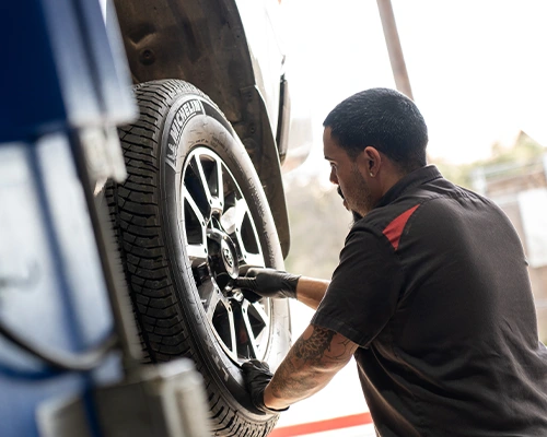 Technician removing wheel from vehicle on lift