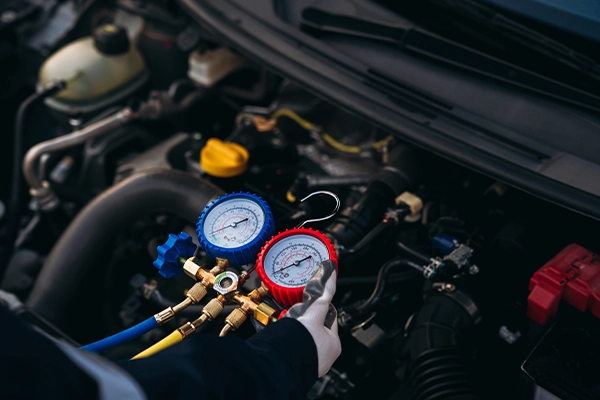 Technician recharging car A/C refrigerant with machine