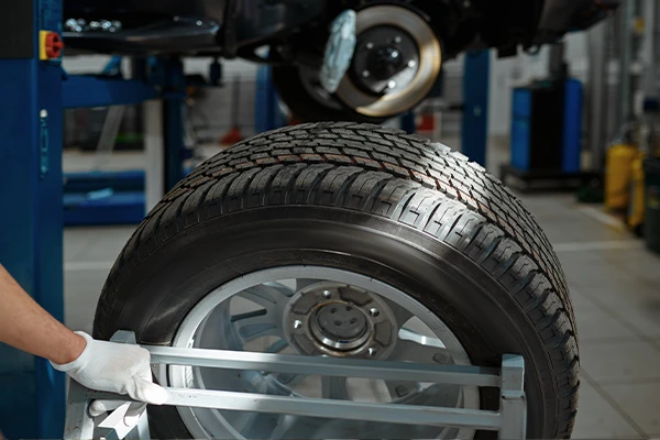 tire sits on the ground next to a vehicle on a lift